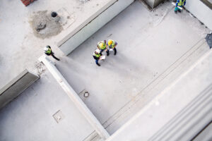 An above view of three people reviewing documents at a commercial construction site in Meridian.