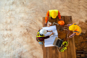 An above view of a team of construction managers reviewing plans at a table at a Meridian construction site.